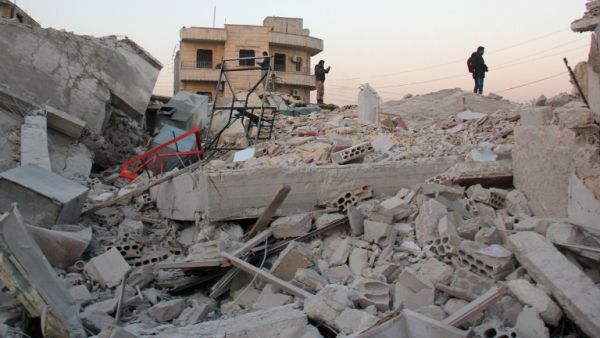 Syrian men stand amidst the rubble of a building following a reported airstrike by government forces, in the Syrian town of Binnish, on the outskirts of Idlib, on January 12, 2017. (AFP/Omar Haj Kadour)