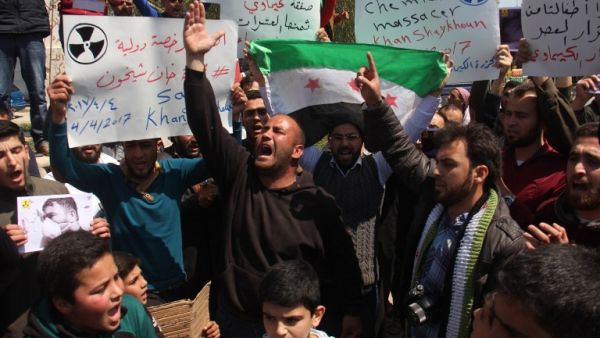 Syrian residents of Khan Sheikhun hold placards and pictures on April 7, 2017 during a protest condemning a suspected chemical weapons attack on their town earlier this week that killed at least 86 people, among them 30 children. (AFP/Omar Haj Kadour)