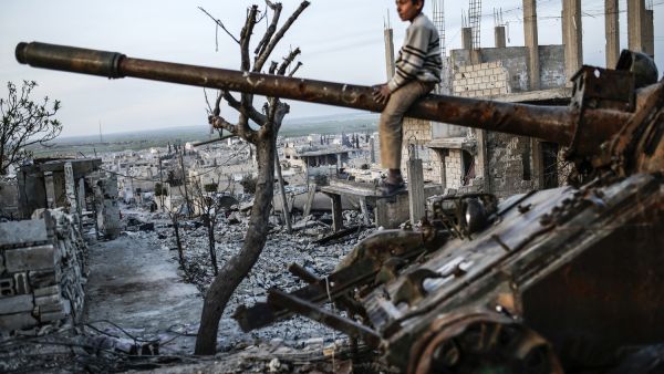 A boy sits on top of a destroyed tank in Syria, AFP/File