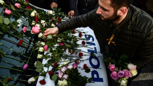 A man lays flowers on a police vehicle as people pay their respects outside the Vodafone Arena football stadium in Istanbul on December 11, 2016, a day after twin bombings near the home stadium of Besiktas football club. (AFP/Yasin Akgul)