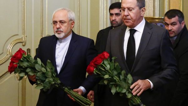 Russian Foreign Minister Sergei Lavrov (R) and his Iranian counterpart Mohammad Javad Zarif lay flowers in front of a photo of Russian ambassador to Turkey, who was killed in Ankara, before their talks in Moscow on December 20, 2016. (AFP/Maxim Shemetov)