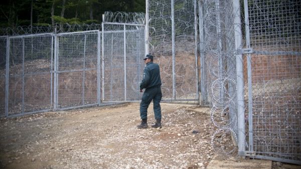 A Bulgarian border police officer stands near a new barbed wire fence at the border between Bulgaria and Turkey near the town of Malko Tarnovo on May 22, 2016. (AFP/Nikolay Doychinov)