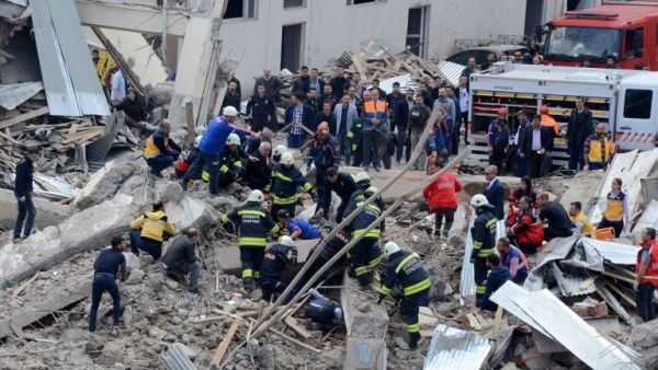 People and emergency workers are seen working at the site of a strong blast near the riot police headquarters in the center of Diyarbakir, southeastern Turkey, on April 11, 2017. (AFP/Ilyas Akengin)