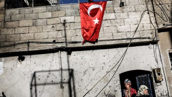 A man hangs a Turkish flag in the border town of Kilis, after Daesh rockets struck the town. (AFP/Yasin Akgul)