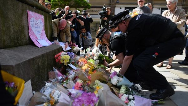 Police officers relocate floral tributes in St Ann's Square in Manchester, northwest England on May 23, 2017, laid as a mark of respect to those in killed and injured following a deadly terror attack at the concert at the Manchester Arena the night before. (AFP/Ben Stansall)
