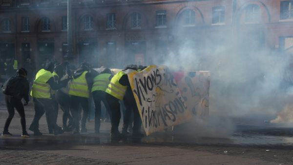 Protesters hide behind a banner amid tear gas smoke during a demonstration in Toulouse, southern France, on February 9, 2019. (AFP/ File)