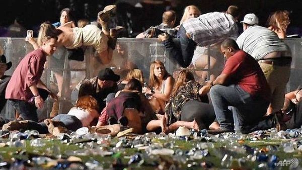 LAS VEGAS: People roll over a wall in a scramble for shelter after a gunman opened fire on an open-air music festival in Las Vegas, killing at least 58 and injuring over 500. (AFP)  