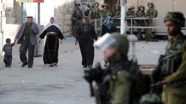 سكان من الخليل يمرون من امام قوات اسرائيلية/أ.ف.ب