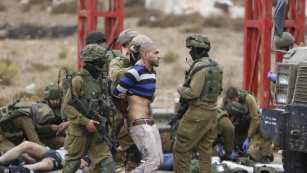 جنود اسرائيليون يعتقلون فلسطينيا بينما يستلقي فلسطينيان اخران مصابان على الارض تحت سيطرة الجنود