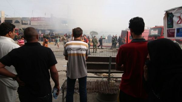 Iraqi passersby stand at the site of a suicide bombing in the Baghdad Jadida area on April 25, 2016. The blast ripped through shops in eastern Baghdad, killing at least seven people. (AFP/Haidar Mohammed Ali)