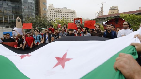 Syrian and Lebanese protesters wave the Syrian flag as they take part in a demonstration in front of United Nations offices in Beirut in solidarity with the civilians of Aleppo on May 1, 2016. (AFP/Anwar Amro)
