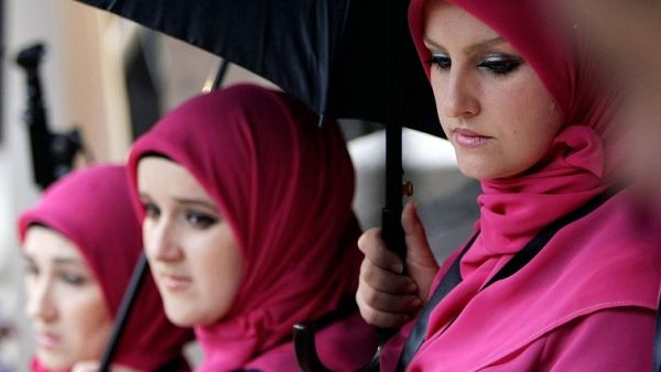Bosnia has become a favored destination for Arab tourists and investors alike.  In the photo: Bosnian women take cover from the rain under umbrellas in Sarajevo, on January 15, 2014. (AFP)
