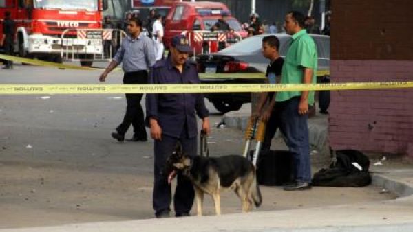 رجل أمن ومعه كلب يستخدم للكشف عن المفرقعات في مسرح انفجار قنبلة بالقرب من جامعة القاهرة
