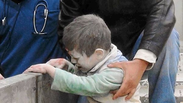 Syrians help an injured child after an alleged airstrike by government forces near a school in Aleppo. (AFP/File) 