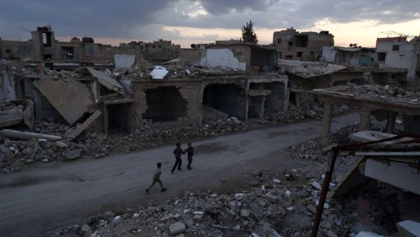 Syrian children walk past heavily damaged buildings in the rebel-held town of Douma, on the eastern edges of the capital Damascus on February 27, 2016. (AFP/Sameer al-Doumy)
