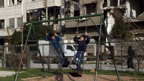 Syrian children play on a swing at a park in the rebel-held town of Douma, on the eastern edges of the capital Damascus on February 27, 2016, on the first day of the landmark ceasefire agreement. (AFP/Samir al-Doumy)