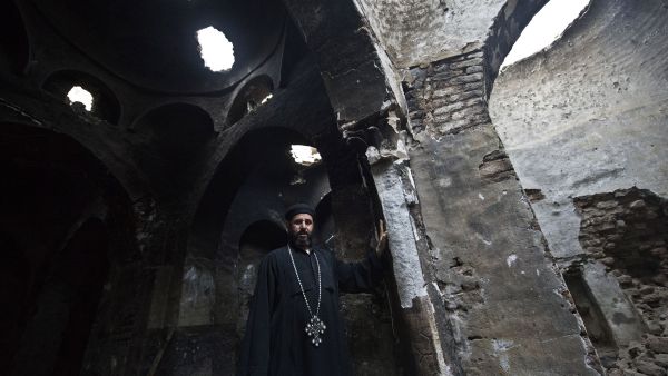 A Coptic priest stands inside what remains of a church after it was attacked by arsonists.  (AFP/Khaled Desouki)