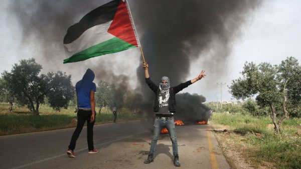 Palestinian demonstrators burn tires during a protest against the nearby demonstration by Israeli right-wing activists calling on Israel to release the suspected Jewish extremists of the July 2015 firebombing the home of a Palestinian family which killed a toddler and both his parents, on April 5, 2016. (AFP/Menahem Kahana)