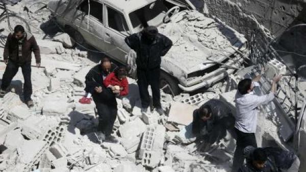 رجل يحمل طفلا وسط أنقاض مباني منهارة بعد ما قال نشطاء إنه ثمانية ضربات جوية للقوات السورية في منطقة دوما في الغوطة الشرقية بالقرب من دمشق
