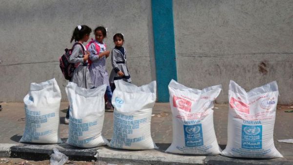 Palestinian Kids pass beside sacks of flour in Gaza Strip. (AFP/ File Photo)
