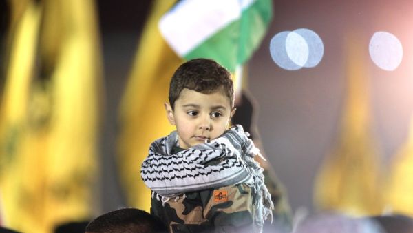 A Palestinian child watches a parade of Palestinian Fatah movement fighters during a rally marking the 50th anniversary of the movement's creation on December 31, 2014. (AFP/Abbas Momani)
