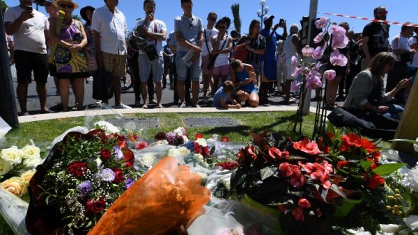 People stand on July 15, 2016 in front of a display in memory of those killed in Nice where a gunman smashed a truck into a crowd of revelers celebrating Bastille Day. (AFP/Boris Horvat)