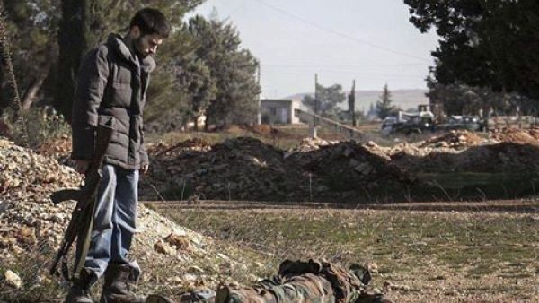 مقاتل في الجيش الحرّ يلقي نظرة على أحد عناصر جيش النظام 