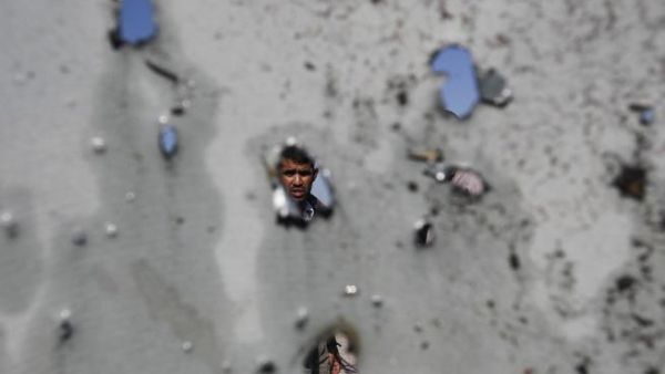 فلسطيني ينظر من خلال الحفر التي احدثتها غارة جوية اسرائيلية في جدران منزله في مخيم جباليا للاجئين الفلسطينيين في غزة/أ.ف.ب
