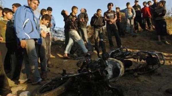 فلسطينيون يتجمعون حول دراجة نارية متفحمة ضربتها غارة جوية اسرائيلية على خان يونس الثلاثاء