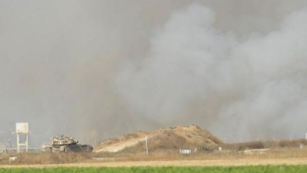 دبابة اسرائيلية ترصد الحدود الجنوبية لغزة فيما تبدو اثار قصف الطيران من بعيد/أ.ف.ب