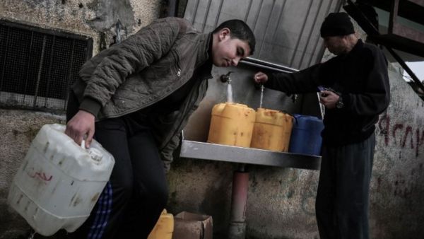 Palestinians fill bottles and jerrycans with drinking water from public taps at the Rafah refugee camp in southern Gaza Strip, on February 22, 2017. (Said Khatib/AFP/File)