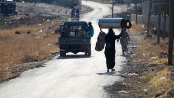 سكان يسيرون على طريق في سهل الغاب في ريف حماة
