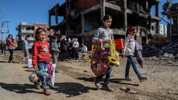 Young girls walk next to ruined houses and shops on March 8, 2016 during International Women's day in Cizre district. (AFP/Ilyas Akengin)