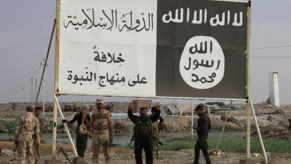 Iraqi fighters pose under Daesh posters near the town of Hit, Iraq. (Twitter)