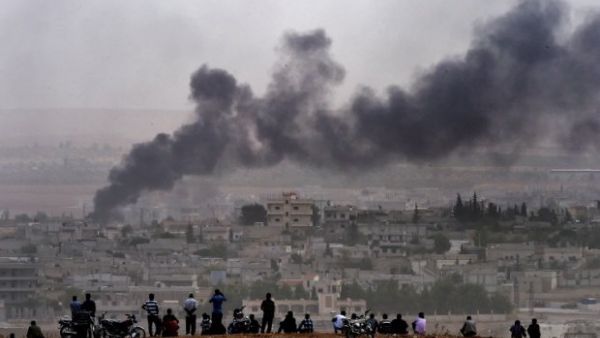 Kurdish people look at the Syrian town of Kobani from the Turkish side of the border. (AFP/Aris Messinis)