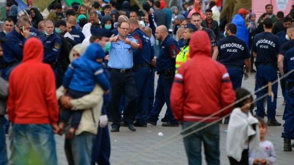 Hungarian police officer directs the migrants in the refugee camp of the Hungarian-Serbian border Roszke village on August 26, 2015. (AFP/Csaba Segesvari)