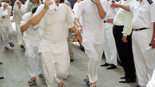 Egyptian men, accused of having gay sex, cover their faces as they walk into a Cairo court 18 July 2001 (AFP File Photo/Andrew Black)