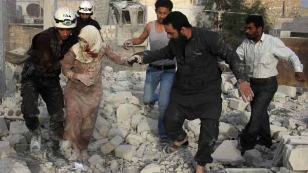 Syrian rescue workers and residents help an injured woman following a reported air strike by government forces on the rebel-held neighborhood of Haydariya in the northern city of Aleppo on April 10, 2016. (AFP/Thaer Mohammed)