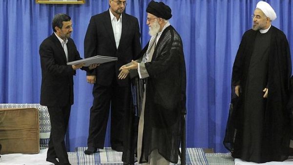 IRAN, Tehran : A handout picture released by the official website of the Iranian supreme leader Ayatollah Ali Khamenei on August 3, 2013, shows Khamenei is given the officially endorsment papers from former president Mahmoud Ahmadinejad as moderate cleric Hassan Rowhani looks on during a ceremony in the capital Tehran.  AFP PHOTO / HO / KHAMENEI.IR