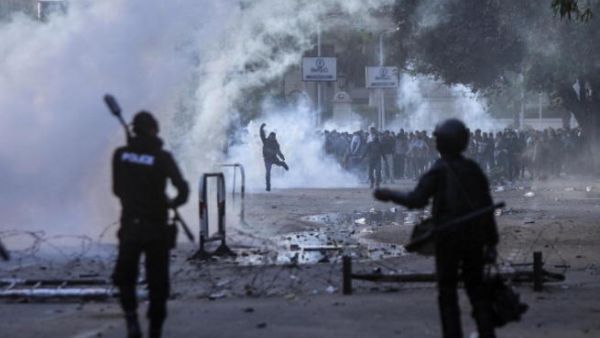 Egyptian students who support the Muslim Brotherhood (background) clash with riot policemen outside the University of Cairo campus in the capital on December 11, 2013. [AFP]