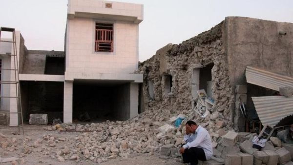 A man squats outside his destroyed home in Shonbeh, after the Bushehr earthquake (AFP)