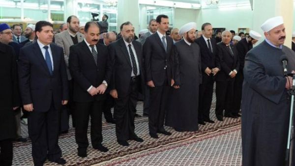 A handout picture released by the official Syrian Arab News Agency (SANA) shows Syrian President Bashar al-Assad next to Syrian Grand Mufti Ahmed Hassun and Syrian Prime Minister Wael al-Halaqi attending prayers on the eve of the anniversary of the birth of Islam's Prophet Mohammed at the al-Hamad mosque in Damascus. [AFP]
