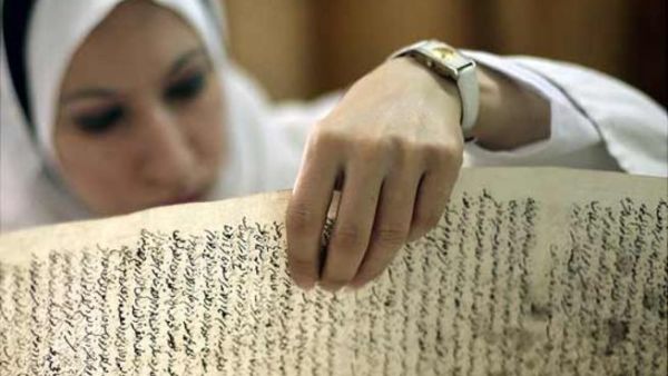 موظفة في المكتبة الوطنية العراقية تتفحص مخطوطا عثر عليه في مكتبة بغداد بعيد الغزو الاميركي

