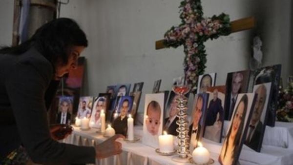 امراة تشعل شمعة وسط صور لمسيحيين عراقيين فتلى في كنيسة سيدة الخلاص في بغداد
