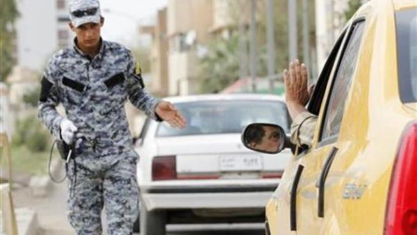 رجل شرطة عراقي يفحص السيارات التي تمر عبر نقطة تفتيش في بغداد 