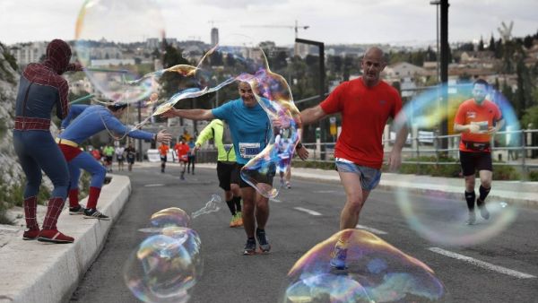 People dressed as "super heroes" make soap bubbles during the 6th Jerusalem's marathon, on March 18, 2016 in Jerusalem's Old City. (AFP/Thomas Coex)