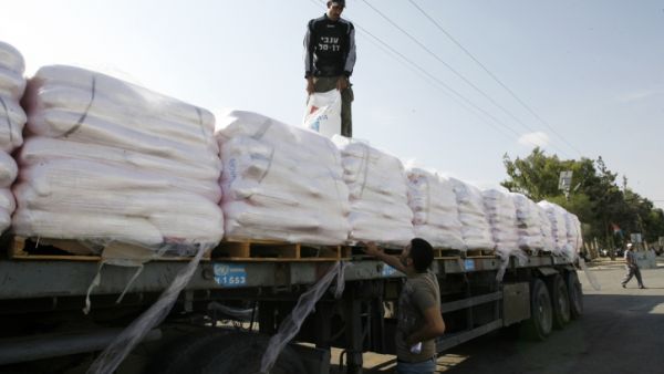 File photo of Palestinian workers offloading a truck full of aid in the Gaza Strip. (Abed Rahim Khatib/Flash90)