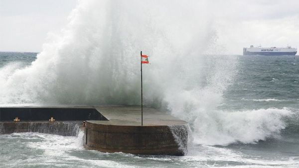 Waves crash into a Lebanese flag during a storm.  While scores of young Lebanese are scrambling abroad for better opportunities, perhaps the key to a better future is to stay home, writes Anthony Elghossain. (AFP/File)