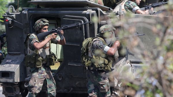 Lebanese Army soldiers take cover behind their armoured vehicle as they enter the Abra neighbourhood on the eastern outskirts of Sidon (Joseph Eid / AFP)