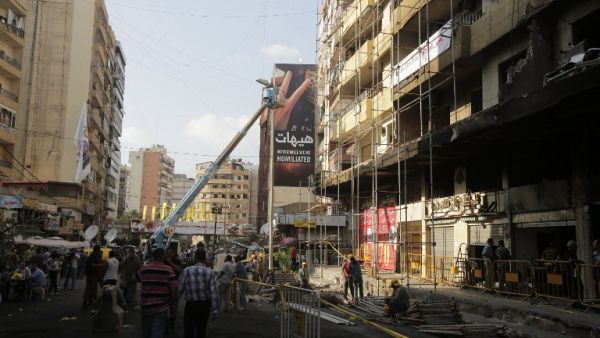 LEBANON, Beirut : Workers from Jihad al-Binaa, a construction company affiliated with the Shiite Muslim Hezbollah movement, clear up the neighbourhood where a car bomb exploded the previous week in a southern Beirut stronghold of the pro-Syria Shiite group on August 19, 2013.  AFP PHOTO/JOSEPH EID